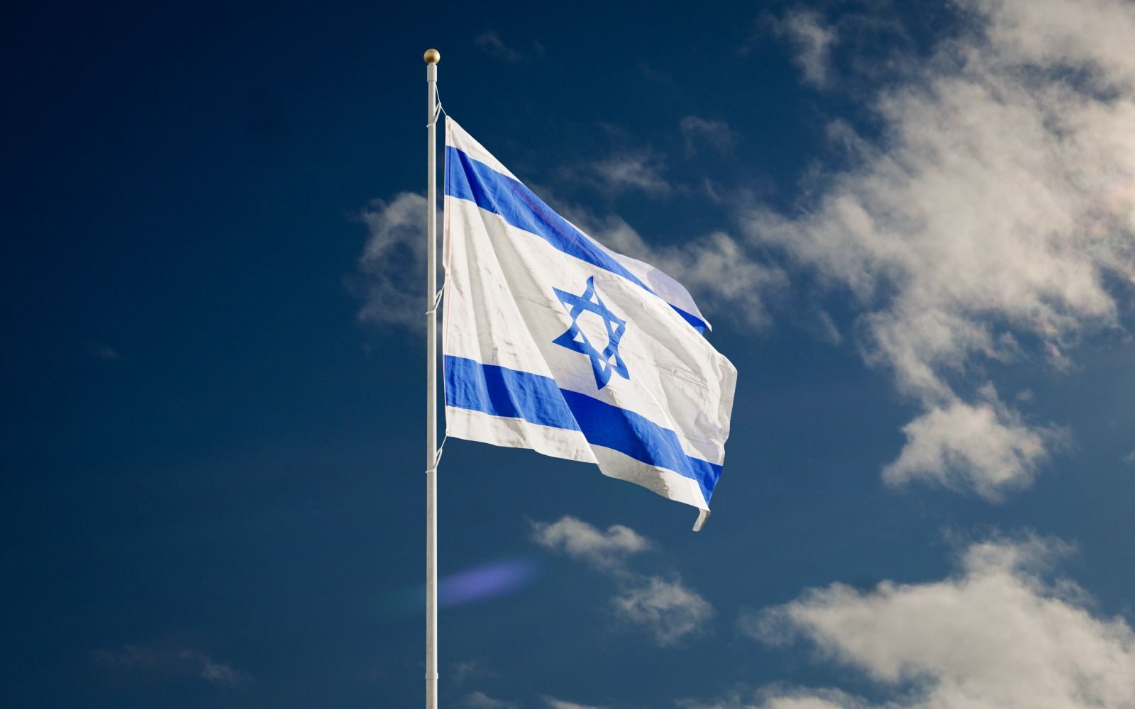 زيارة نتنياهو إلى أبوظبي تفتح باب التساؤلات.. تحركات جوية لافتة تزامنت مع الزيارة 1 The Israeli national flag waving against a clear blue sky with clouds.